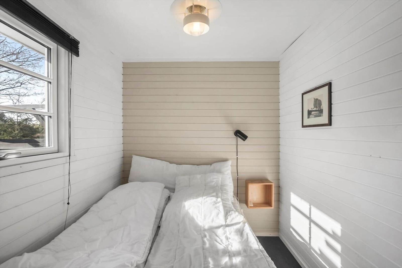Bedroom with bed, window, and wall paneling.