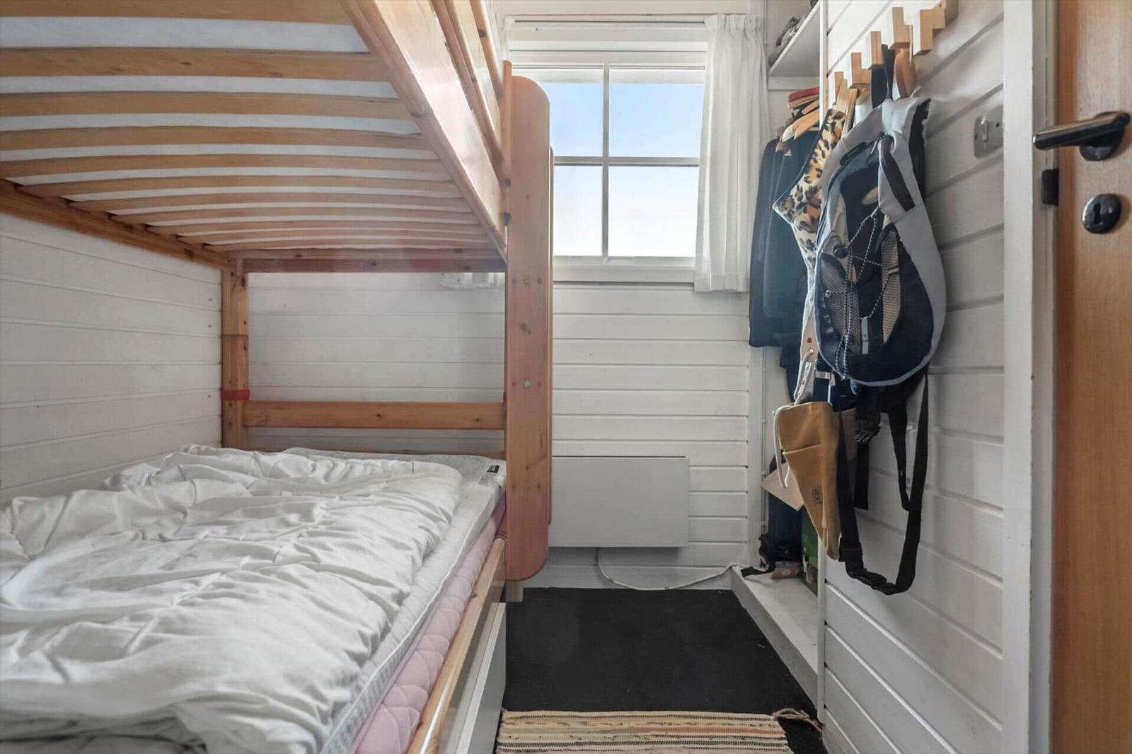 Small bedroom with bunk bed, window, and hooks on the wall.