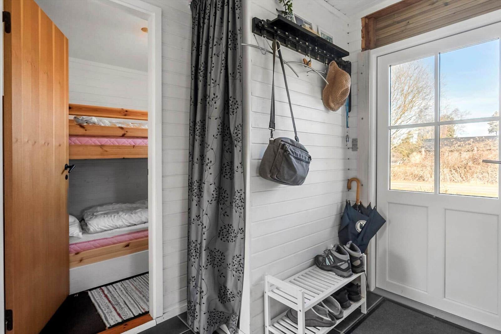 Entrance with coat rack, shoe rack, and view into bedroom with bunk bed.