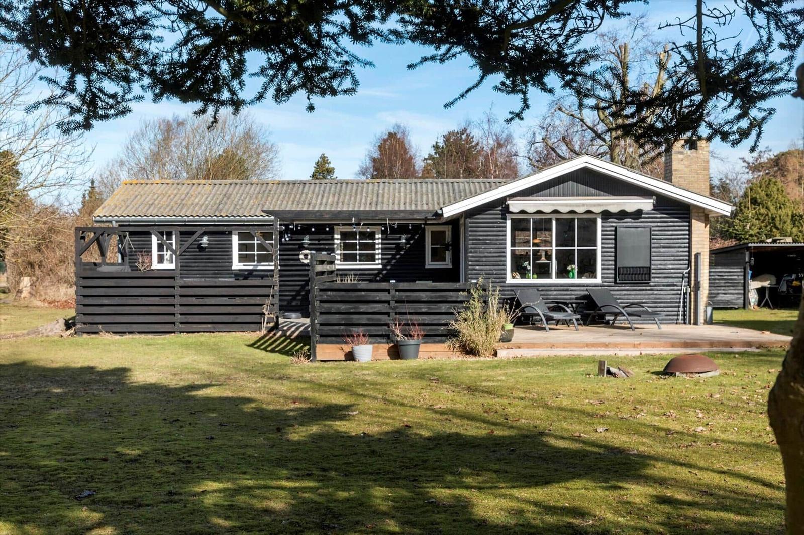 Black wooden house with terrace and garden. View of the exterior.