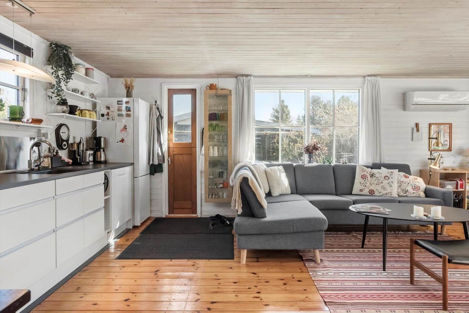Living kitchen with gray sofa, wooden floor, and large windows.
