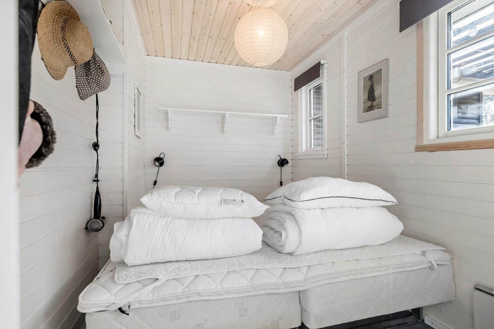 Bedroom with white bed, wooden ceiling, and window.