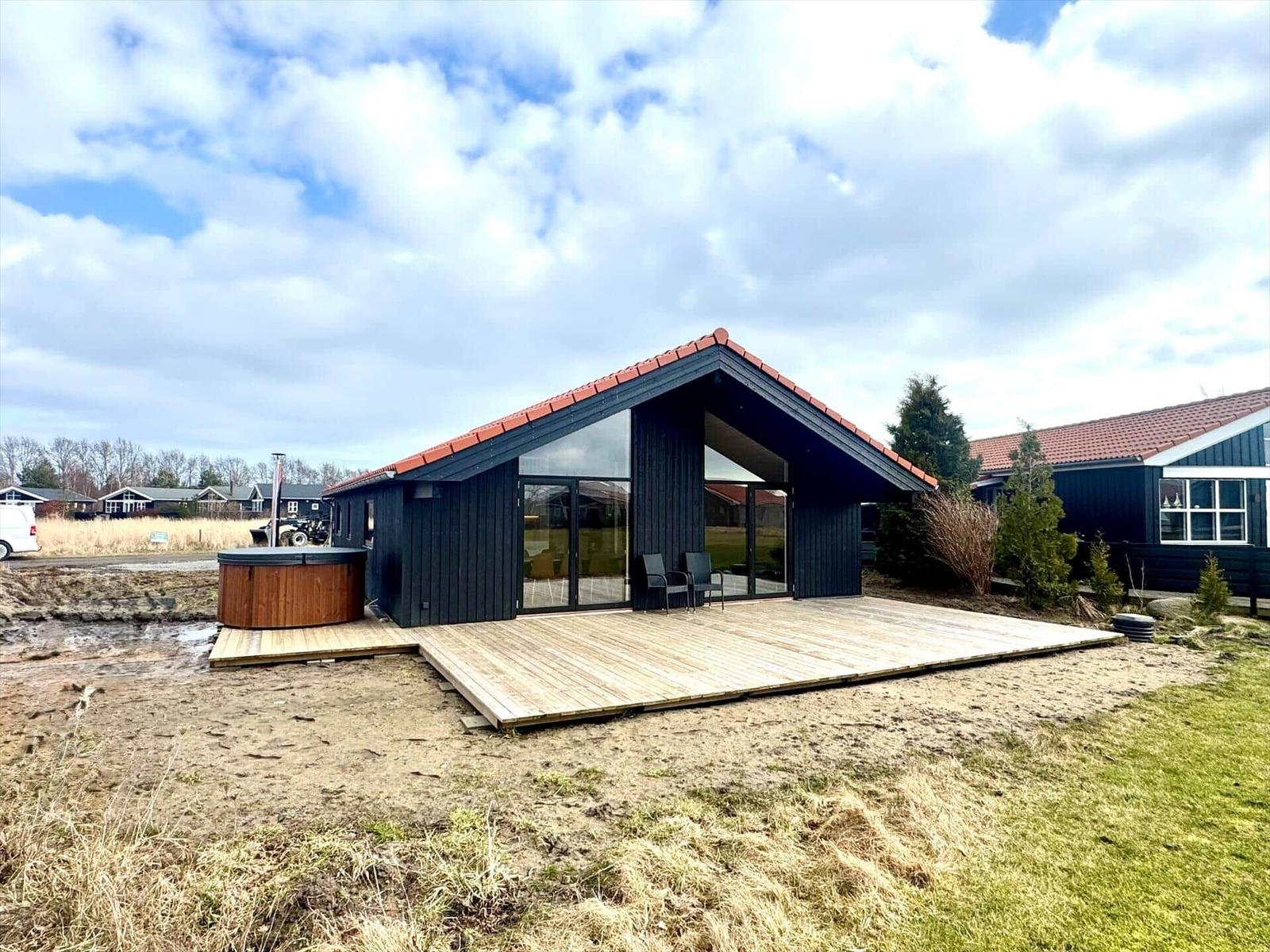Modern villa with wooden terrace and hot tub. View of the garden and sky.