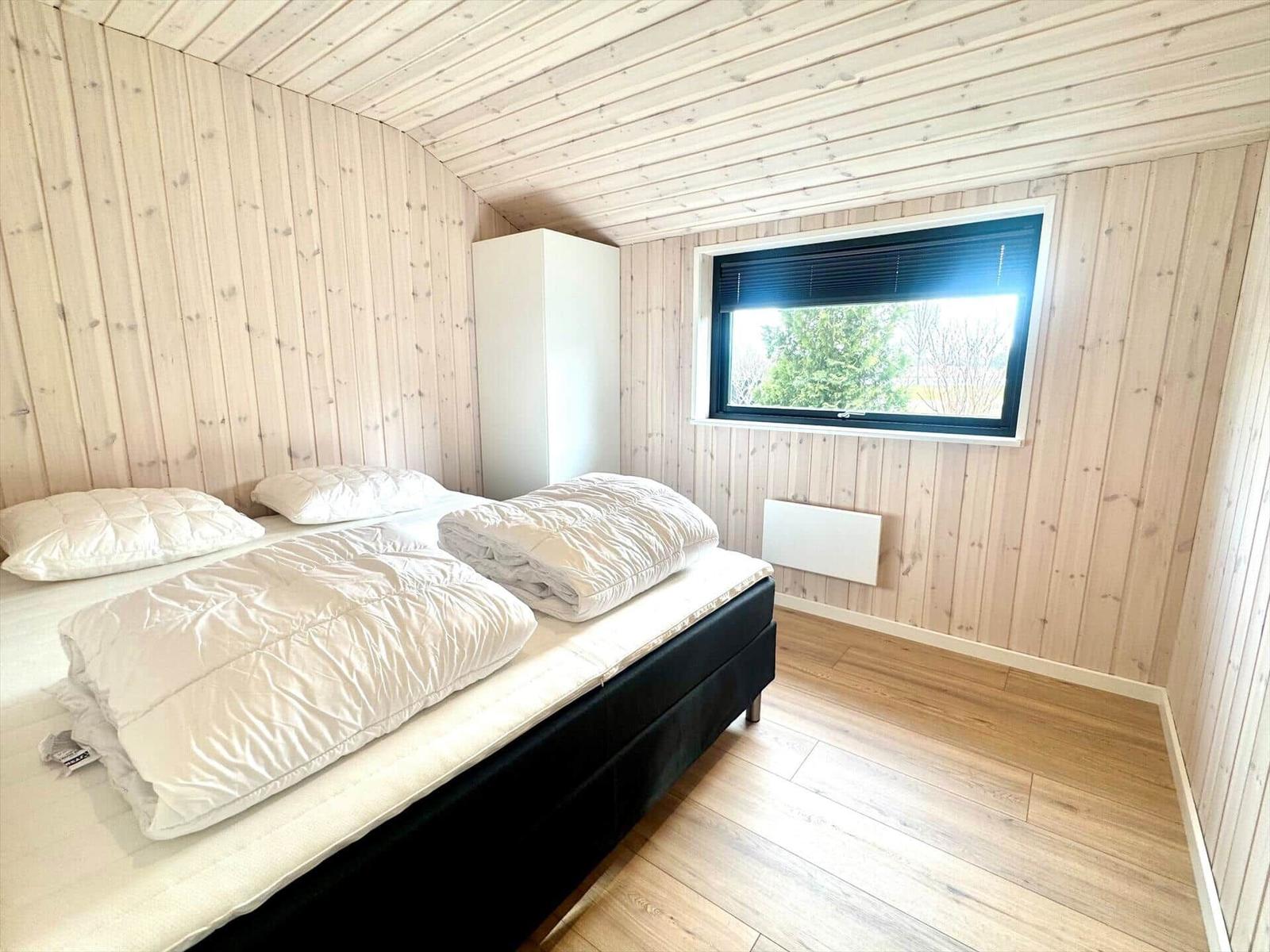 Bedroom with wooden walls, bed, and window