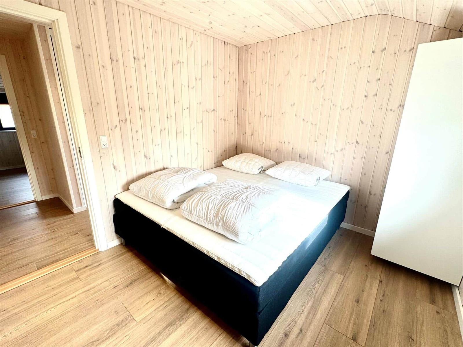 Bedroom with wooden walls and bed with white pillows.