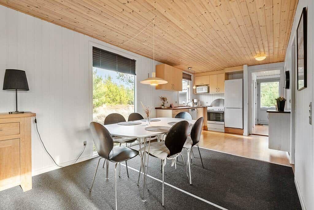 Essbereich mit Tisch, Stühlen und Blick auf Küche.