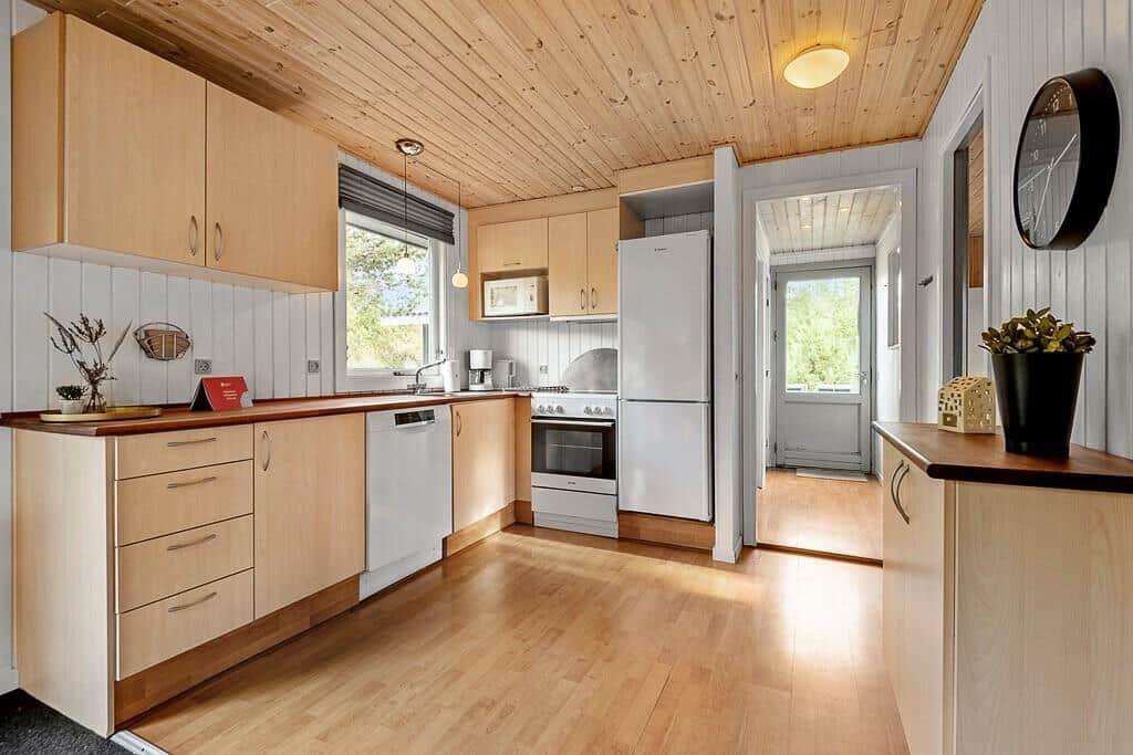 Küche mit Holzboden, hellen Schränken und moderner Küchenausstattung.