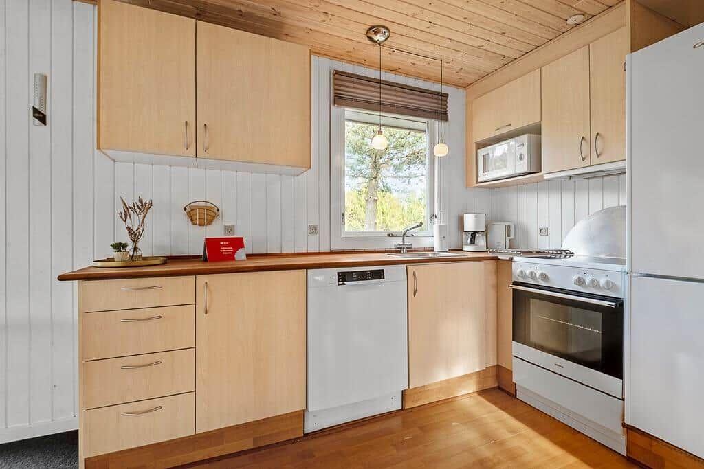Küche mit Holzschrank, Spüle, Herd und Fenster.