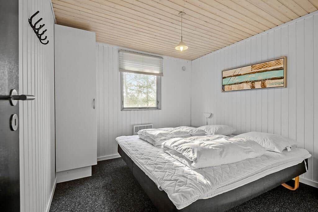Schlafzimmer mit Bett, Fenster und Wandbild.