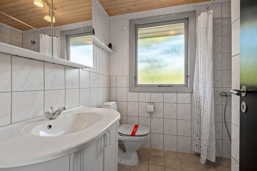 Badezimmer mit Waschbecken, Toilette und Dusche. Fenster mit Milchglas.