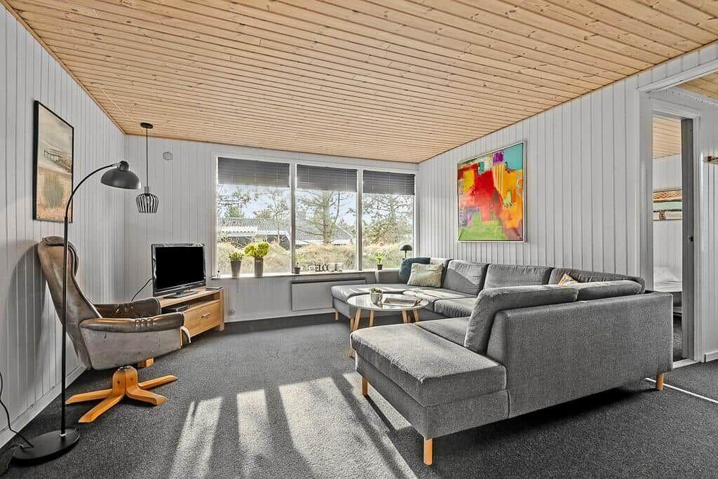 Wohnzimmer mit grauem Sofa, Fernseher und großem Fenster.