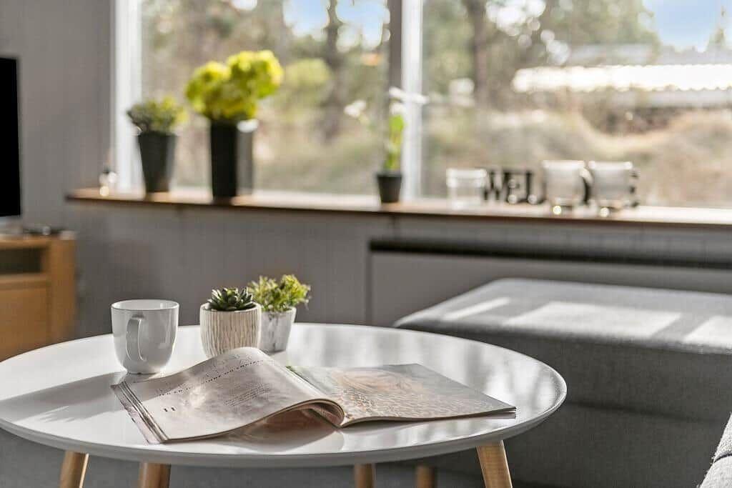 Rundtisch mit Tasse, Zeitschrift und Pflanzen vor Fenster