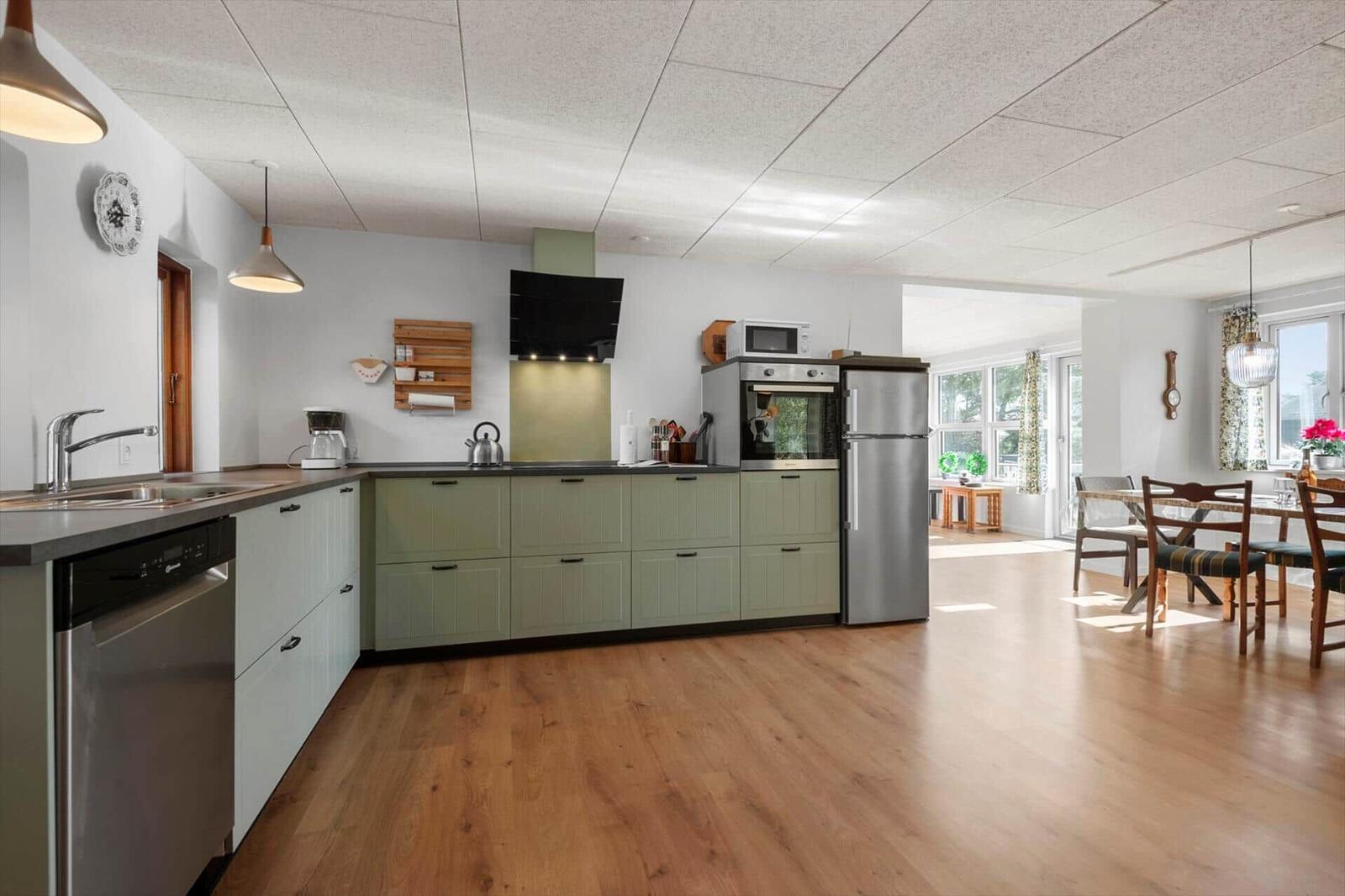 Küche mit Arbeitsplatte, Spüle und Küchengeräten. Essbereich mit Tisch und Stühlen.