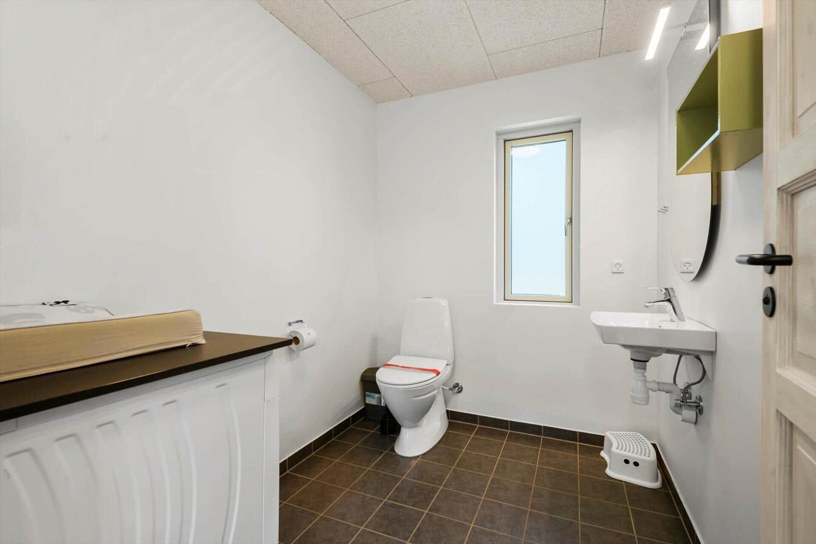Badezimmer mit Toilette, Waschbecken und Fenster.