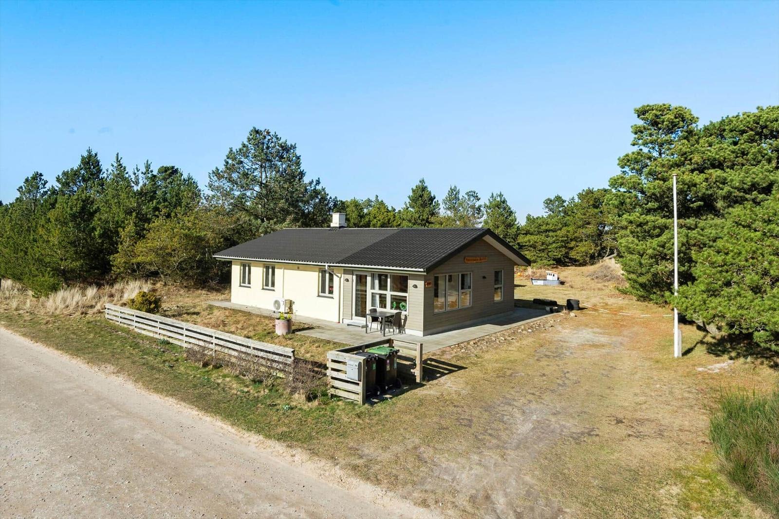 Ein kleines Haus mit Terrasse, umgeben von Bäumen und Grasland.