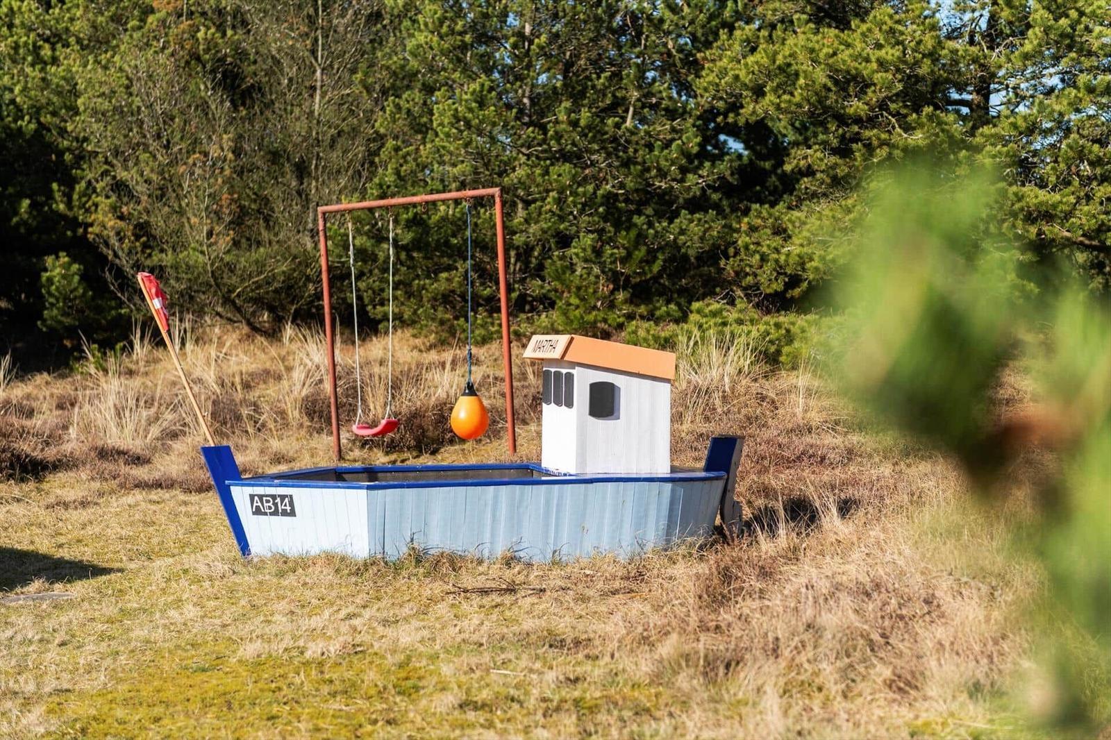 Ein Spielboot mit Schaukel und orangefarbenem Schwimmer im Freien.