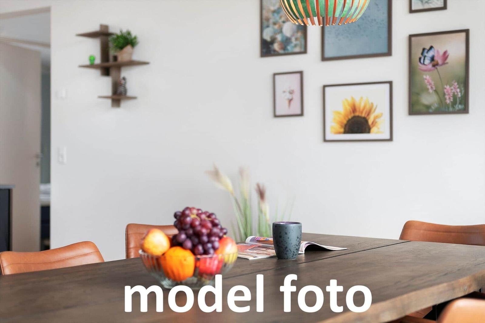 Esstisch mit Obstschale, Bechern und Bildern an der Wand.