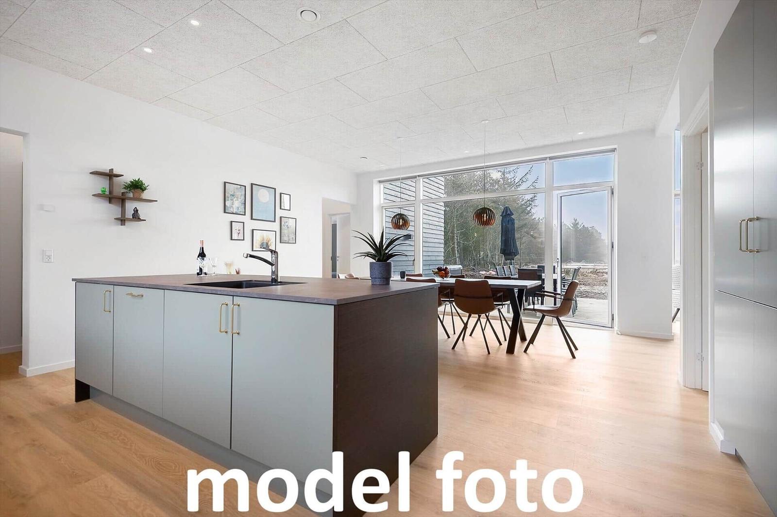 Küche mit Insel und Essbereich mit Tisch und Stühlen. Große Fensterfront mit Blick auf Garten.