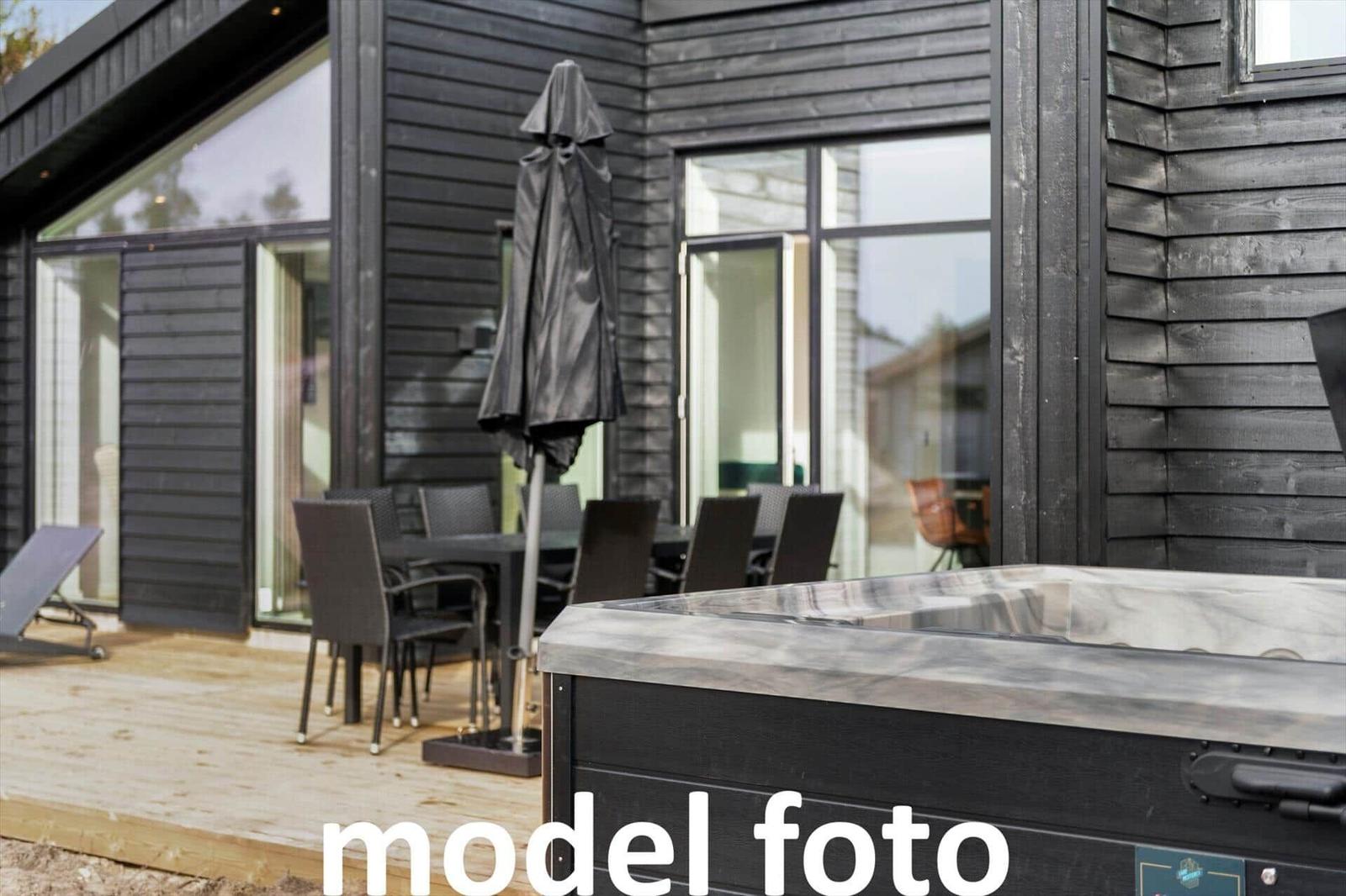 Außenbereich mit Hot Tub, Terrasse und Sitzgruppe vor einem modernen Holzhaus.
