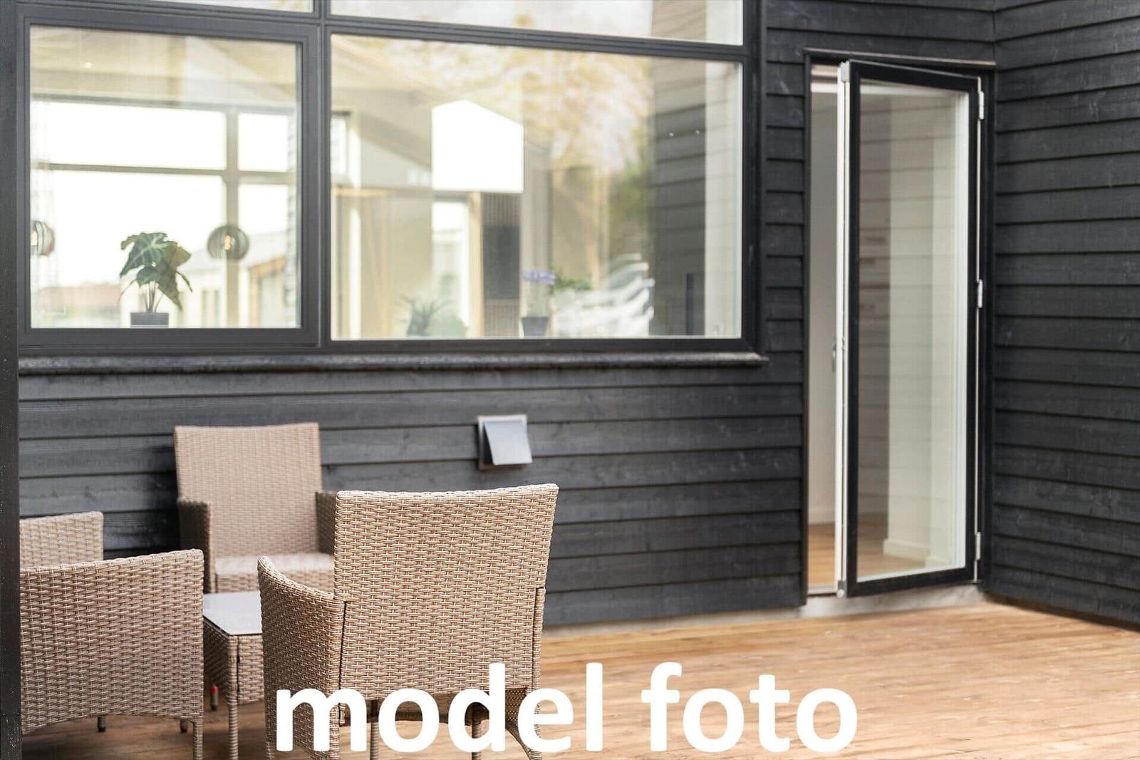Terrasse mit Rattanmöbeln und Glas-Tür zu Wohnraum