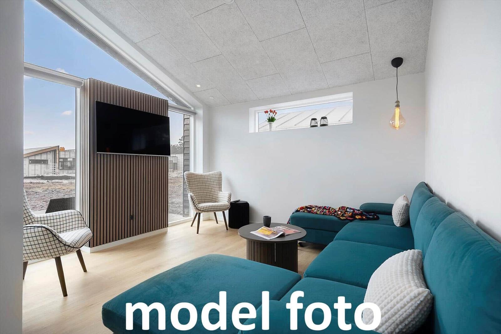 Ein Wohnzimmer mit blauem Sofa, Fernseher und großem Fenster.