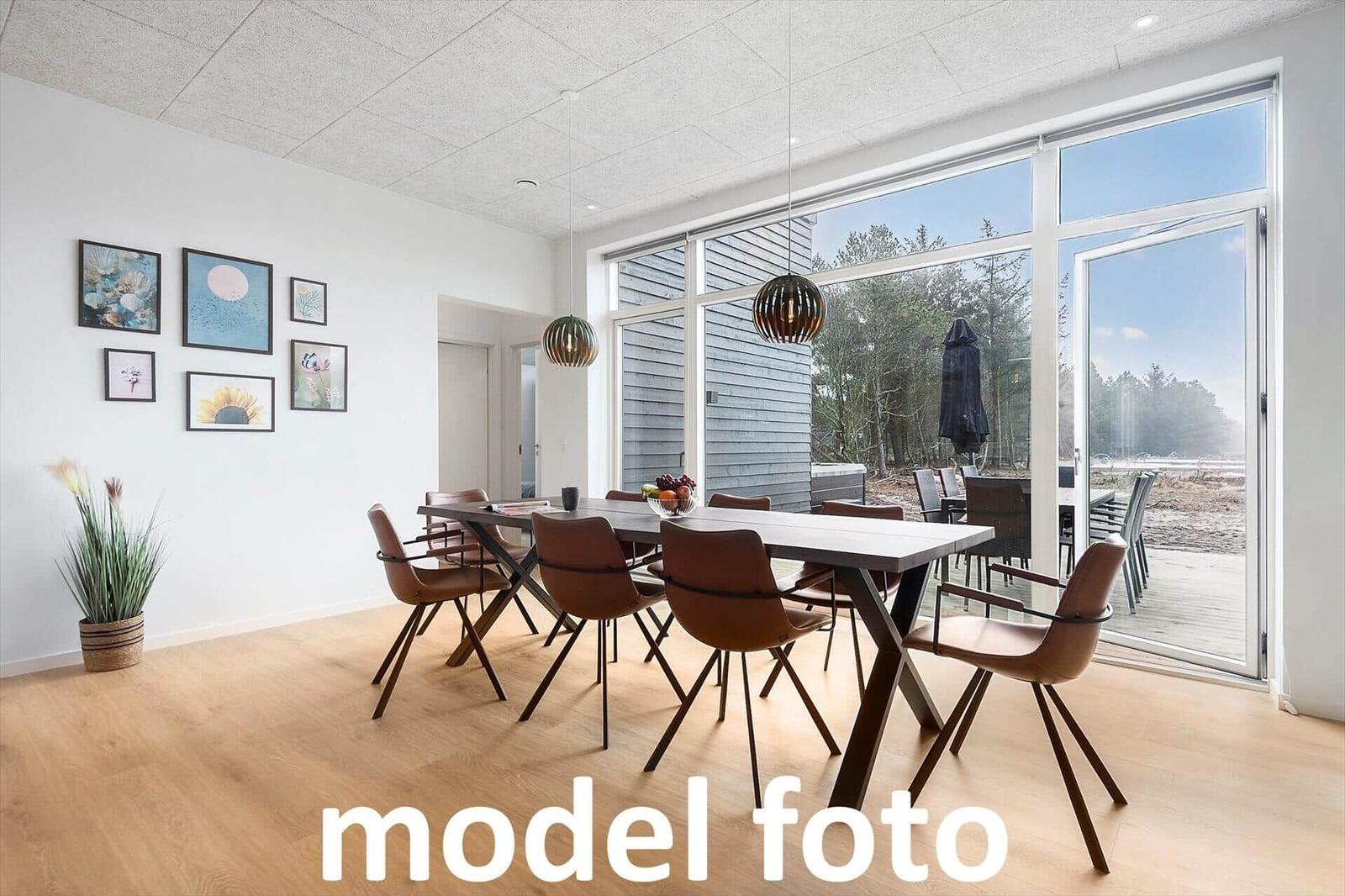 Esszimmer mit Tisch, Stühlen und großem Fensterblick auf die Terrasse.