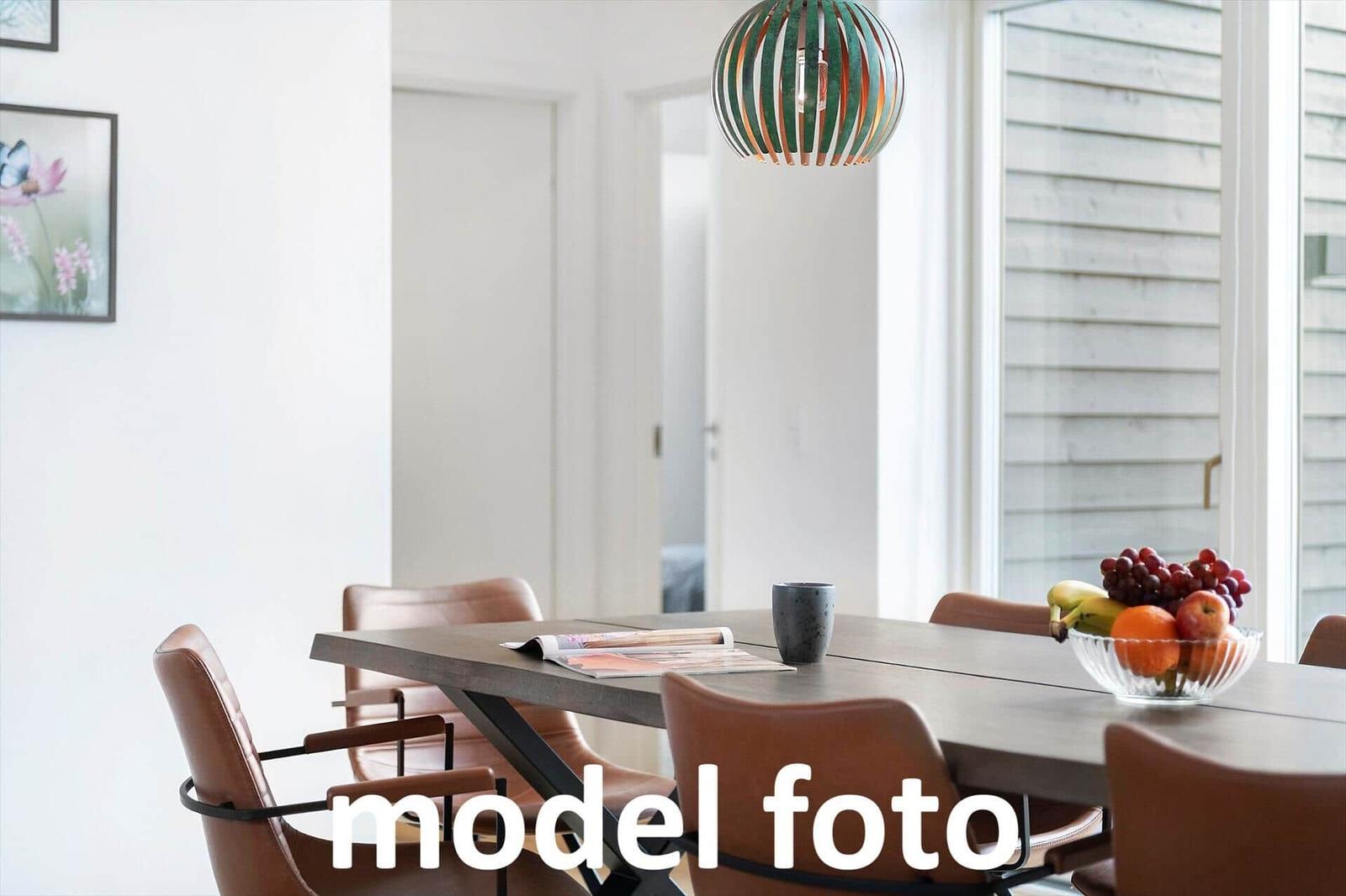 Esstisch mit braunen Stühlen und Obstschale unter einer Lampe.