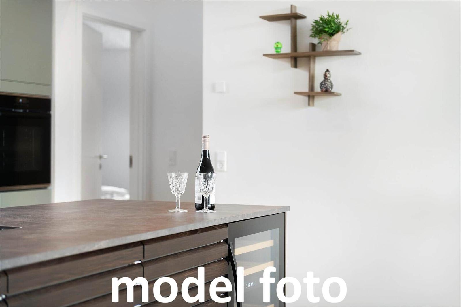 Küche mit Holzoberfläche, Weinflasche und Gläsern, Wandregal mit Pflanze und Dekoration.