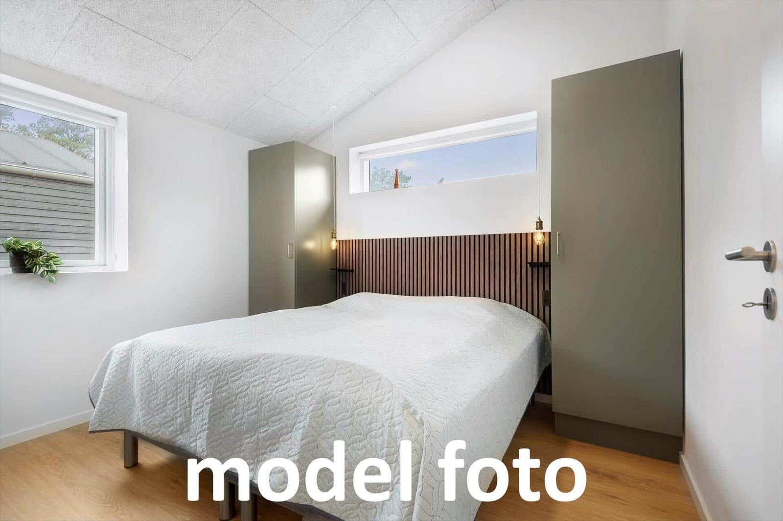 Schlafzimmer mit Bett, Holzfußboden und Fenstern.