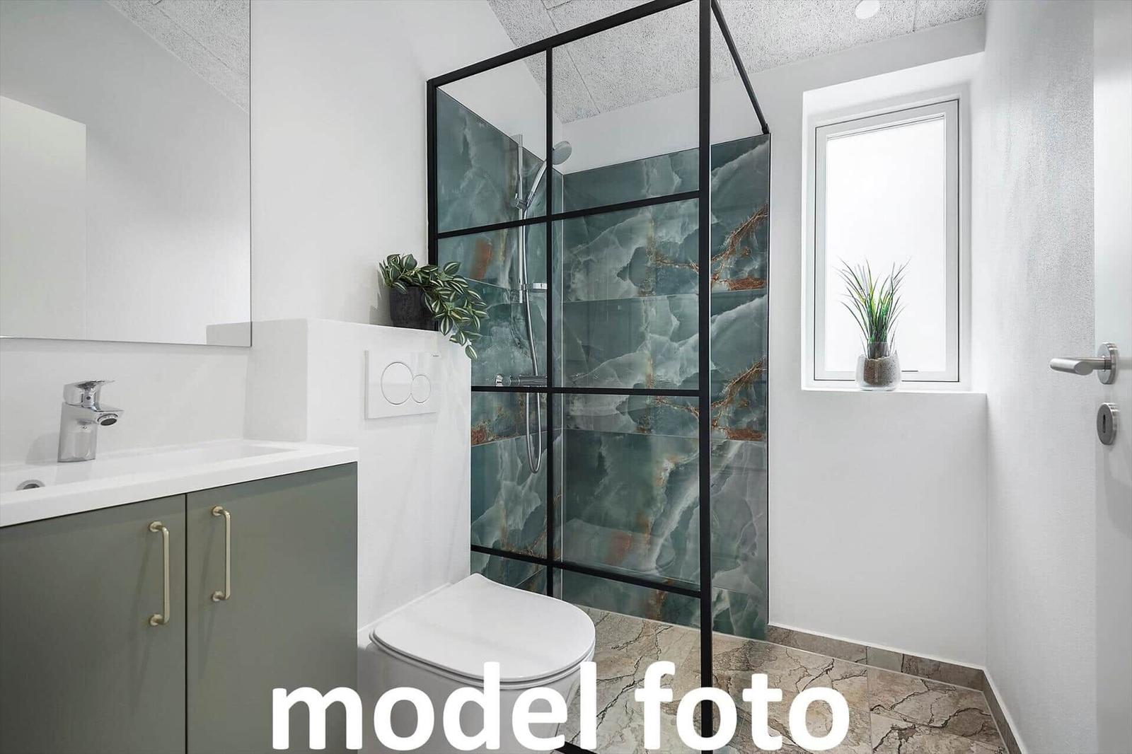 Badezimmer mit Dusche, Waschbecken und Toilette. Fenster mit Pflanze.