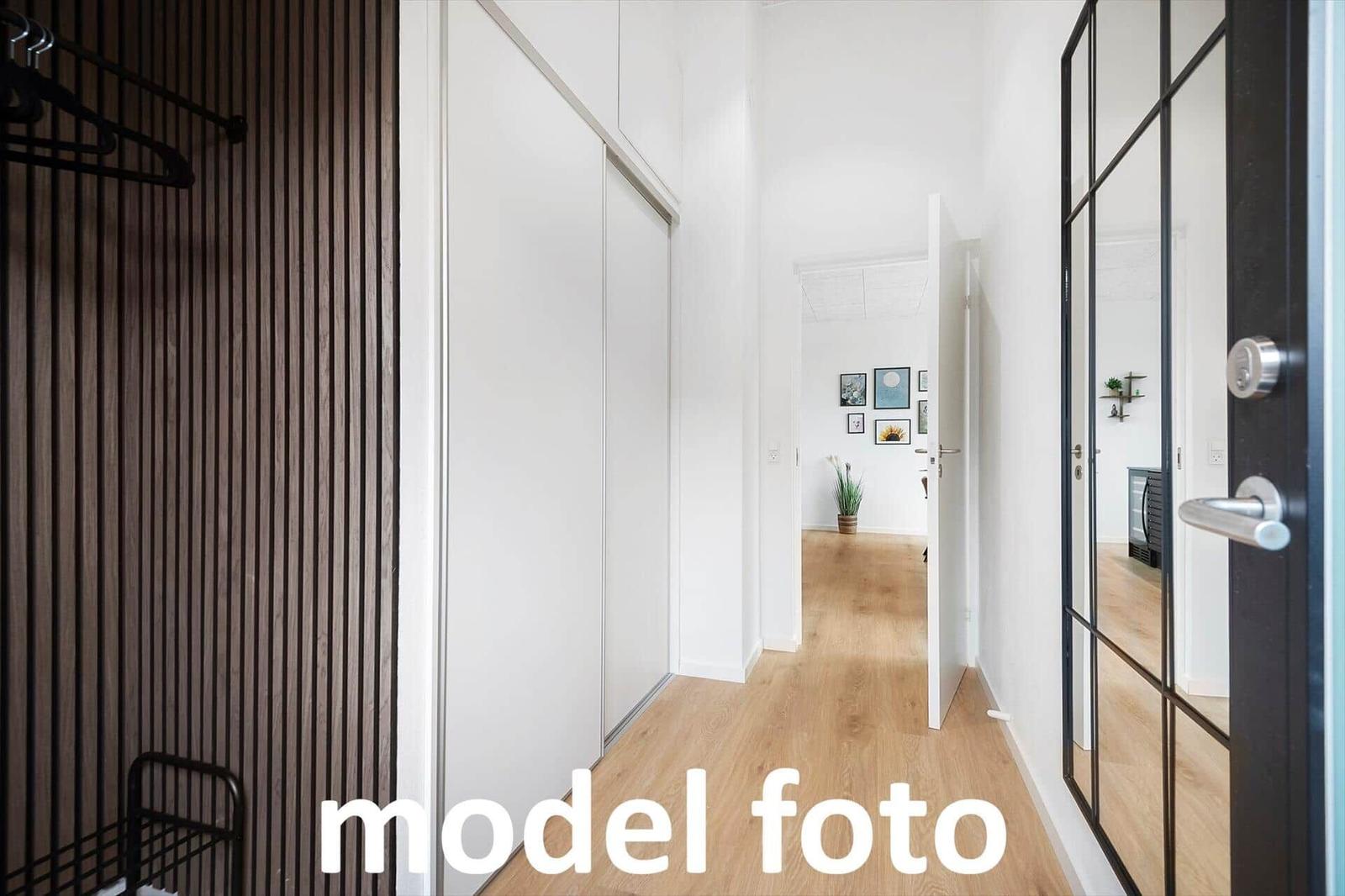 Flur mit Holzboden, Schiebetüren und Spiegeltüren. Im Hintergrund ist ein Zimmer mit Pflanze und Bildern.