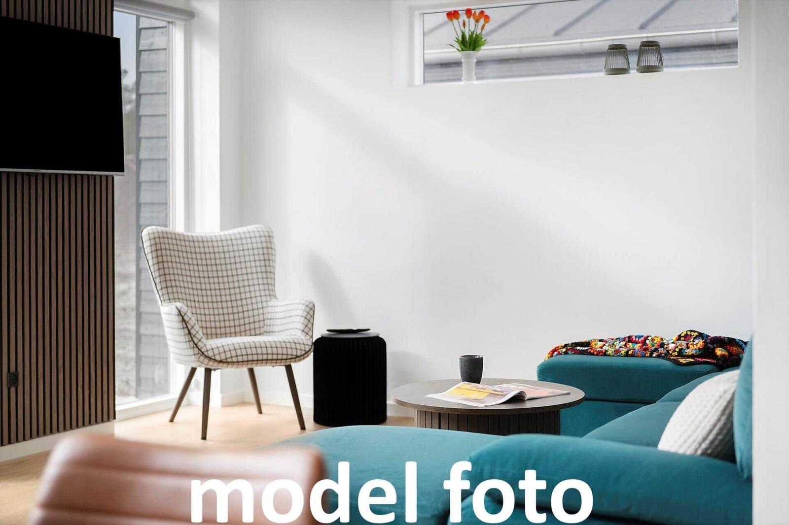 Ein Wohnzimmer mit blauem Sofa, gemusterter Sessel und runder Tisch.