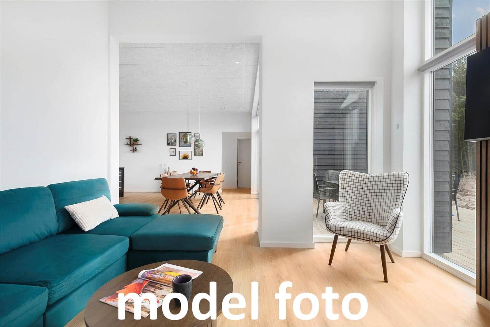 Wohnzimmer mit Sofa, Sessel und Essbereich. Holzboden und große Fenster.