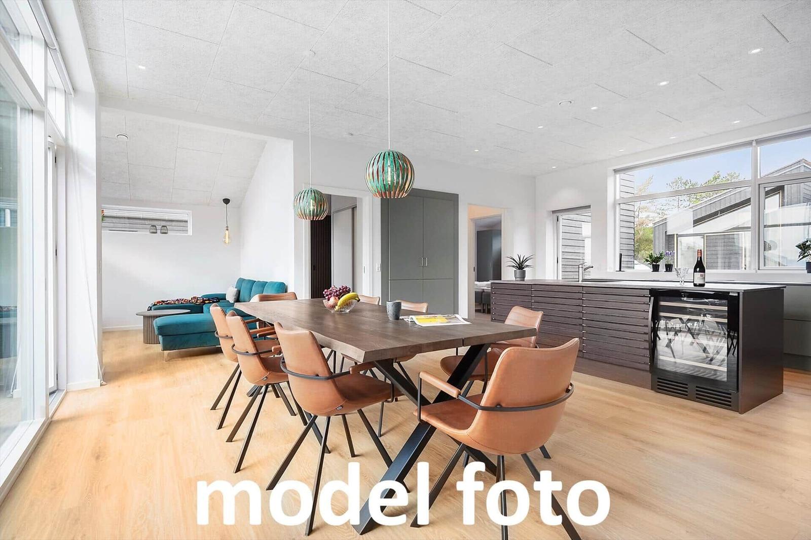 Essbereich mit Holztisch, Lederstühlen und Kücheninsel mit Kühlschrank.