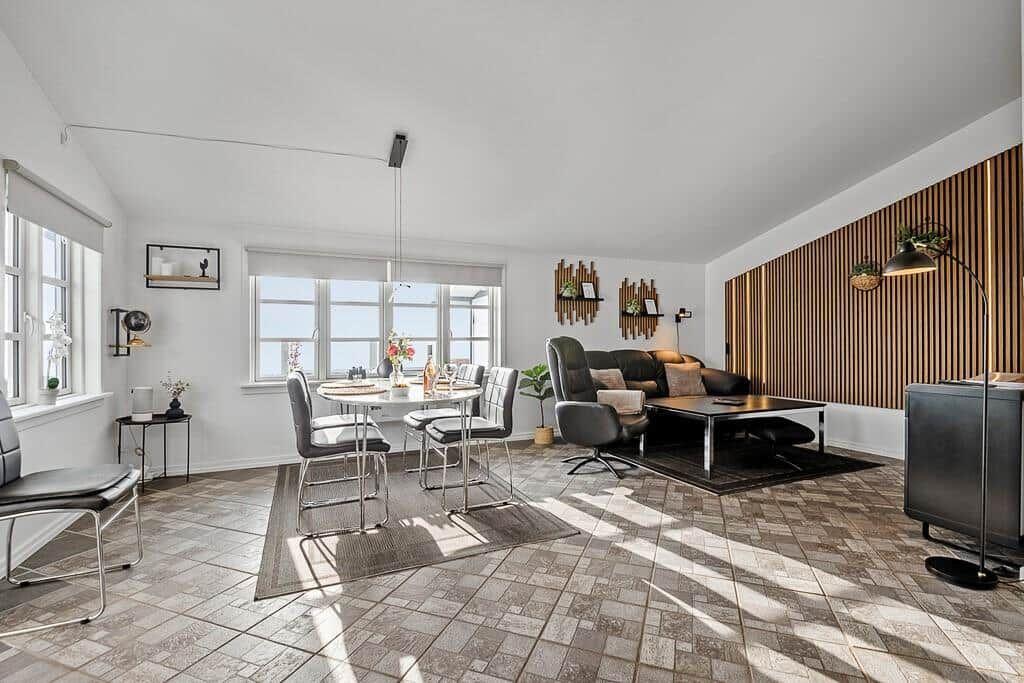 Wohn- und Essbereich mit Tisch, Stühlen, Sofa und Holzwand.