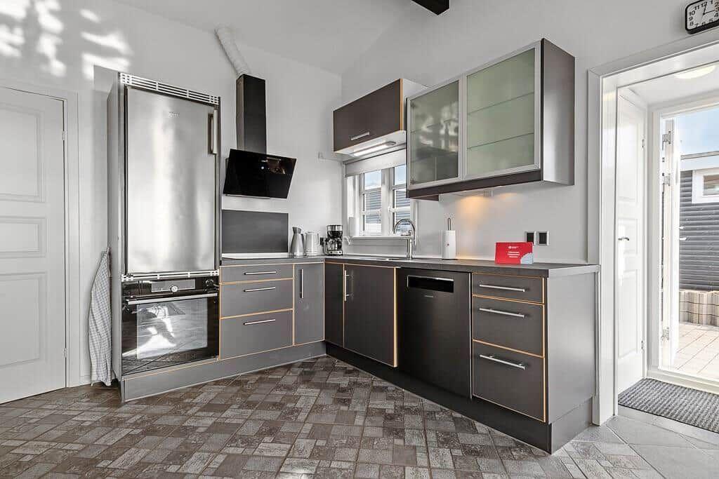 Moderne Küche mit Edelstahl-Kühlschrank und dunklen Schränken.