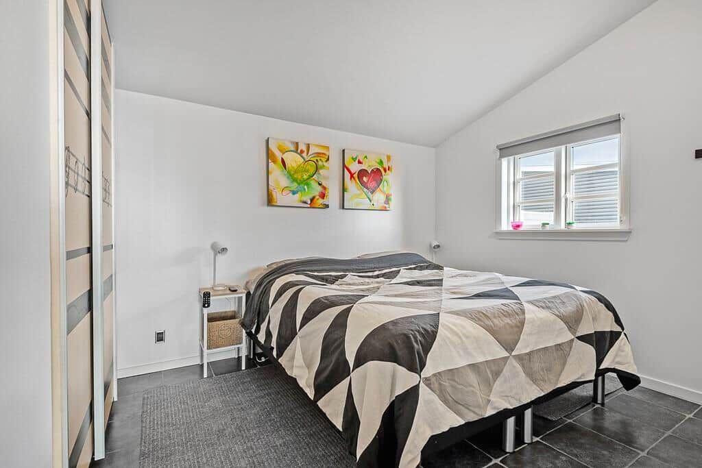 Schlafzimmer mit Bett, Fenster und zwei Wandbildern.