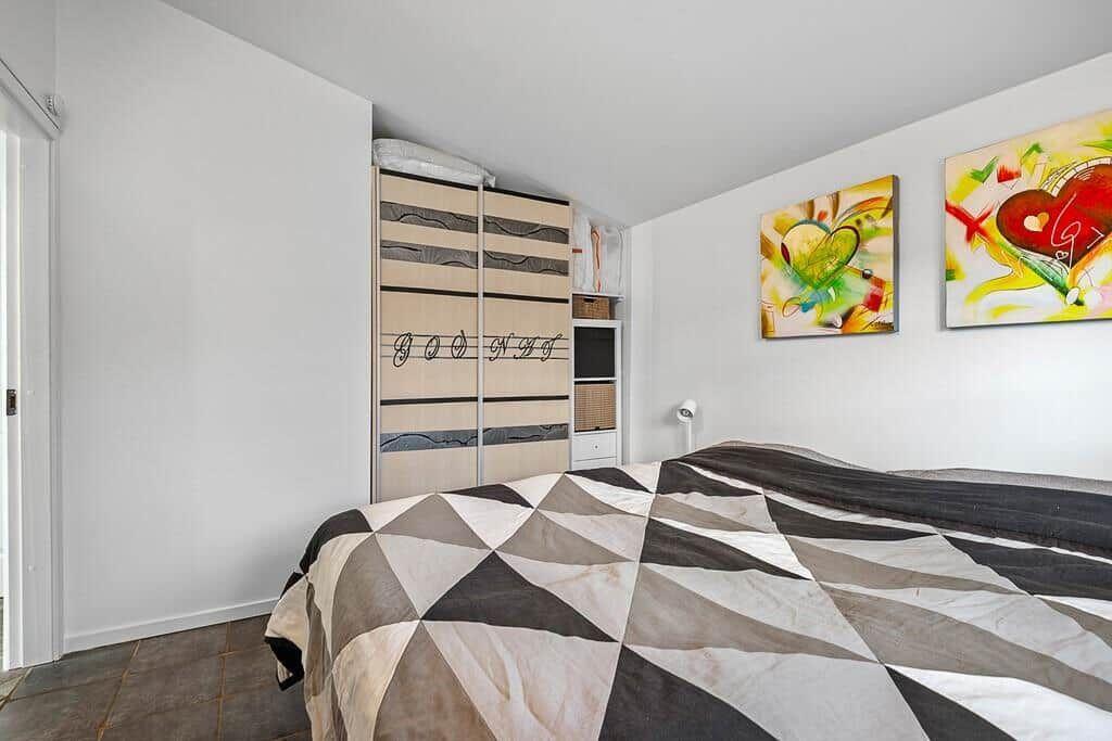Schlafzimmer mit Bett, Kleiderschrank und Wandbildern.
