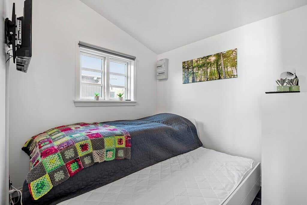 Schlafzimmer mit Bett, Fenster, Wandbild und TV.