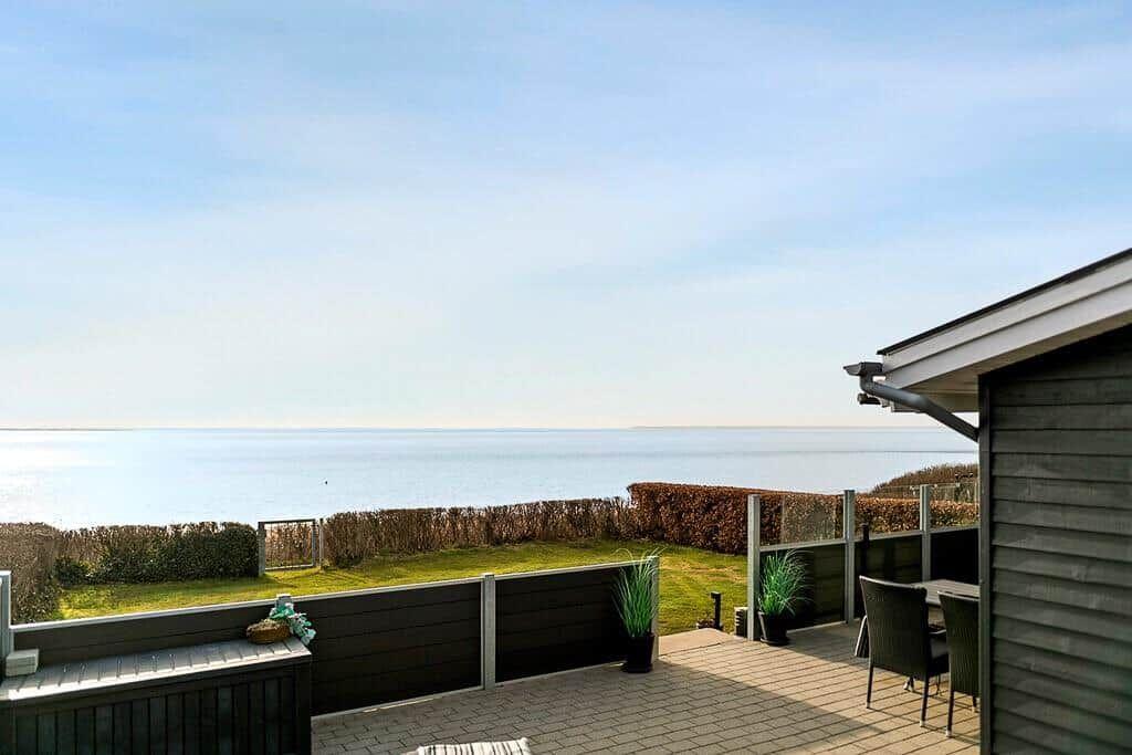 Terrasse mit Blick auf das Meer und grünen Rasenbereich.