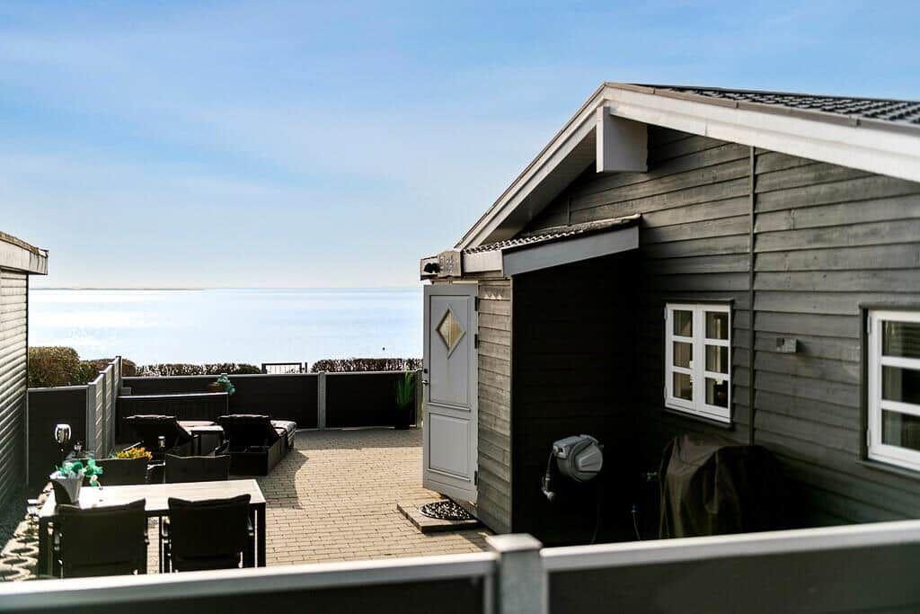 Terrasse mit Meerblick, Sitzgelegenheiten und Holzhaus.