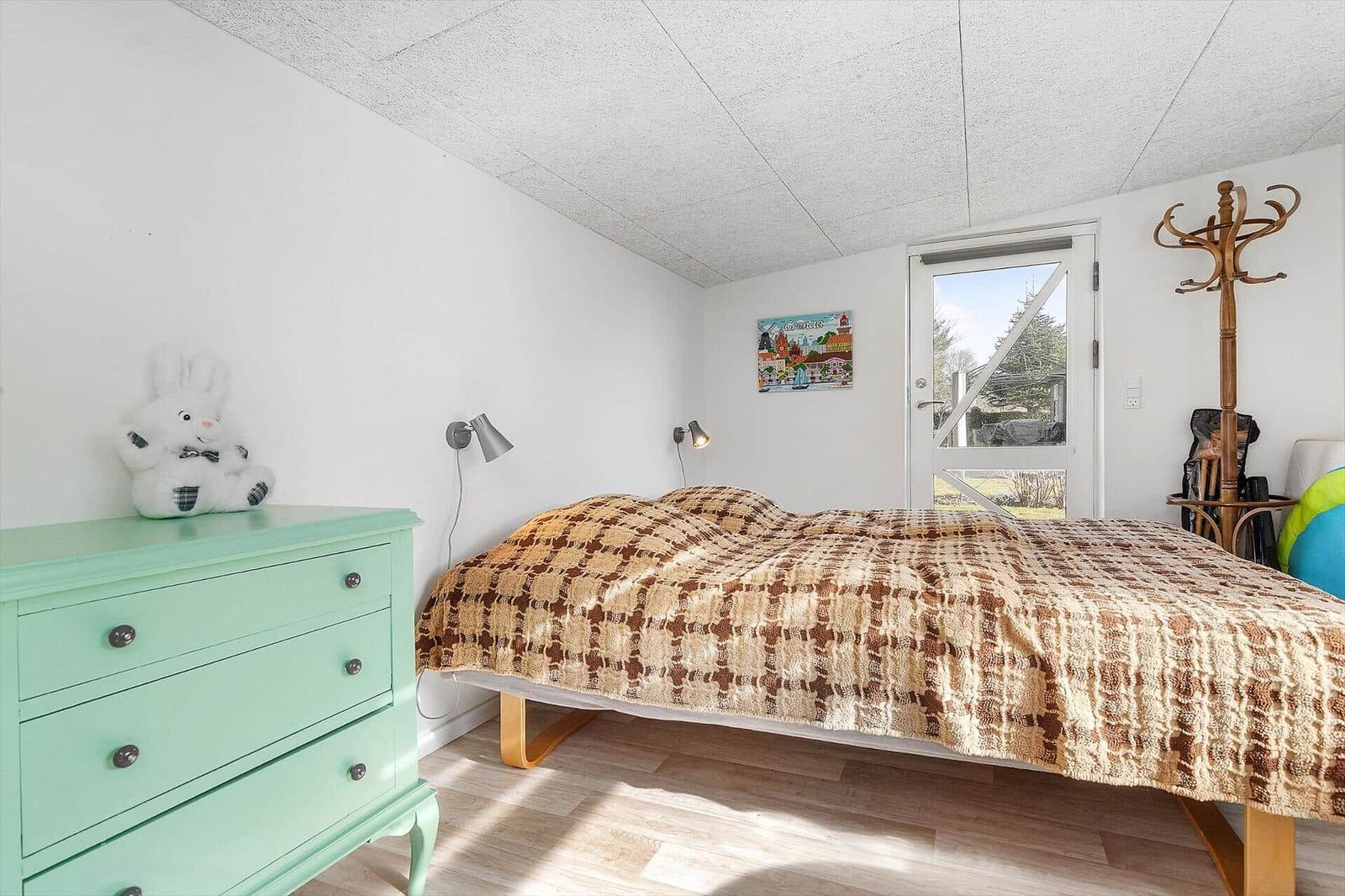 Schlafzimmer mit Bett, Kleiderschrank und Tür zum Garten.