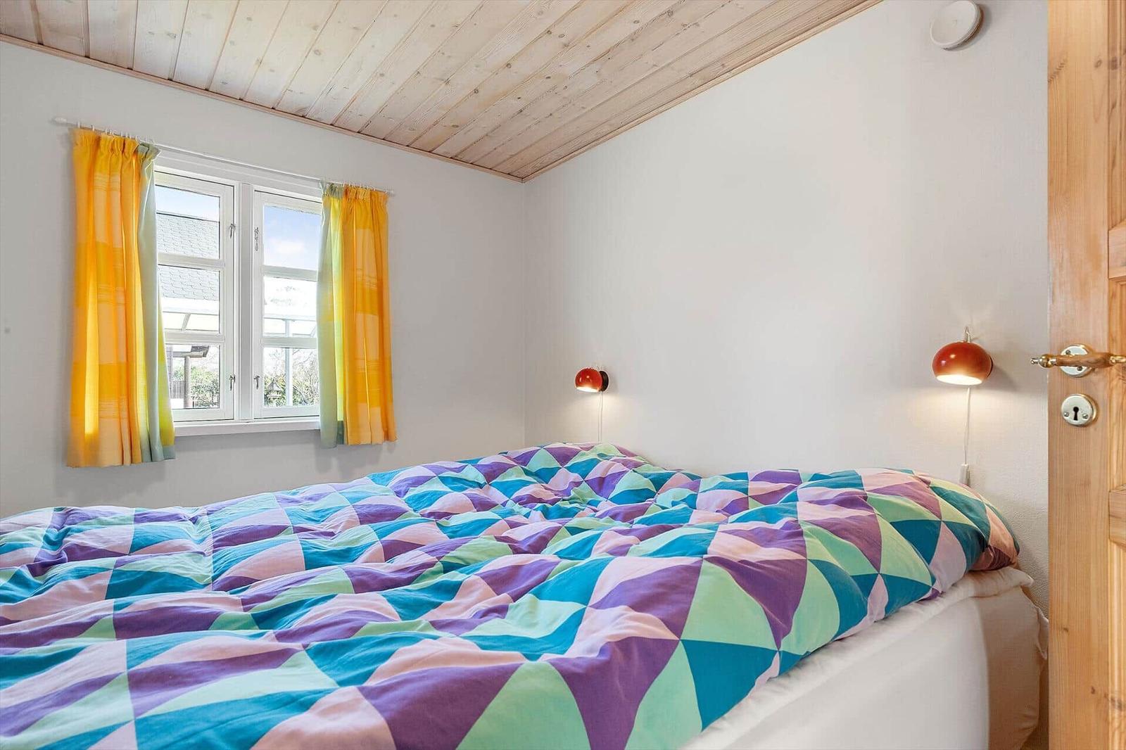 Schlafzimmer mit Bett, Fenster und Holzdecke.
