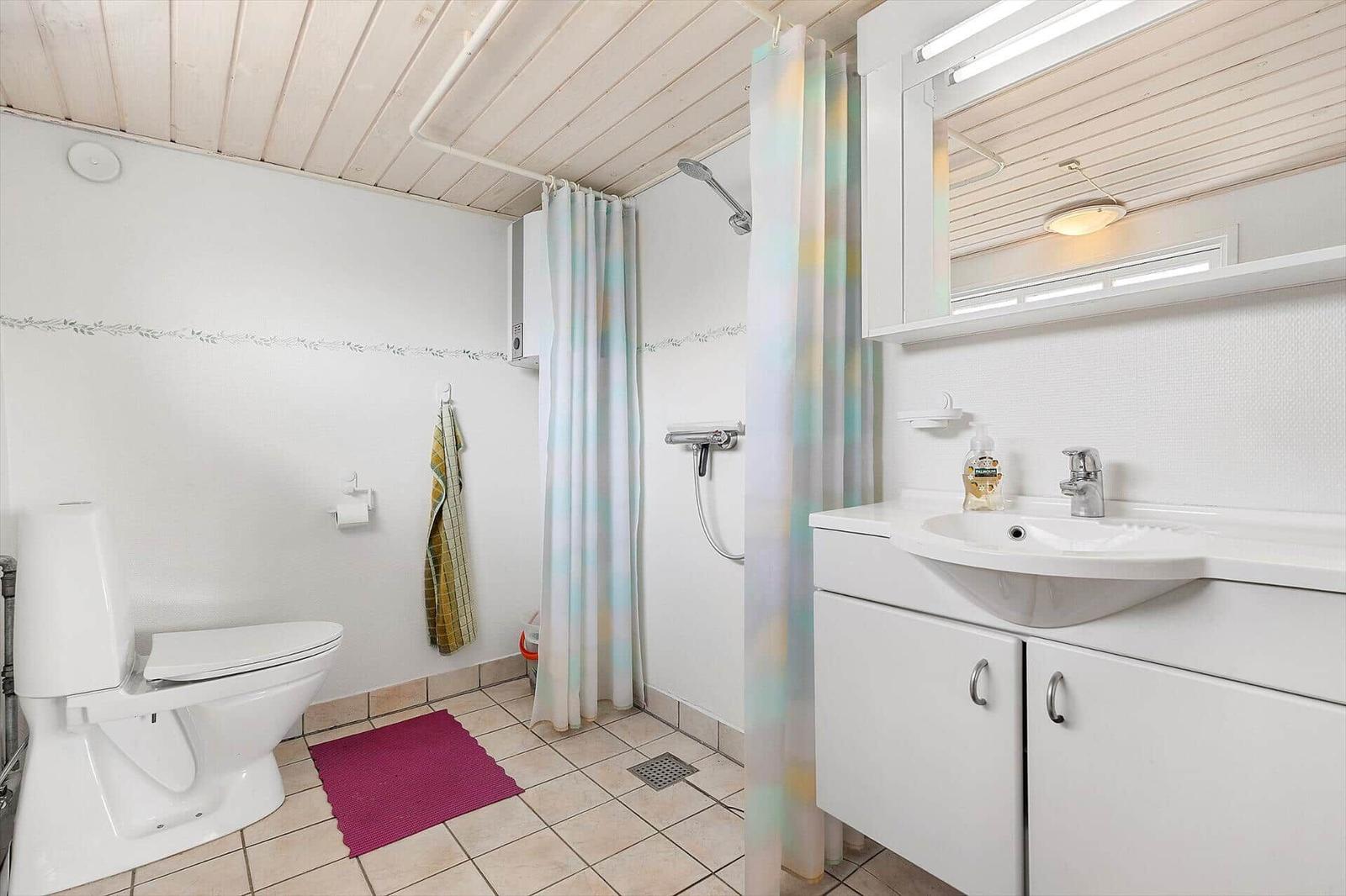 Badezimmer mit Toilette, Dusche und Waschbecken mit Spiegel