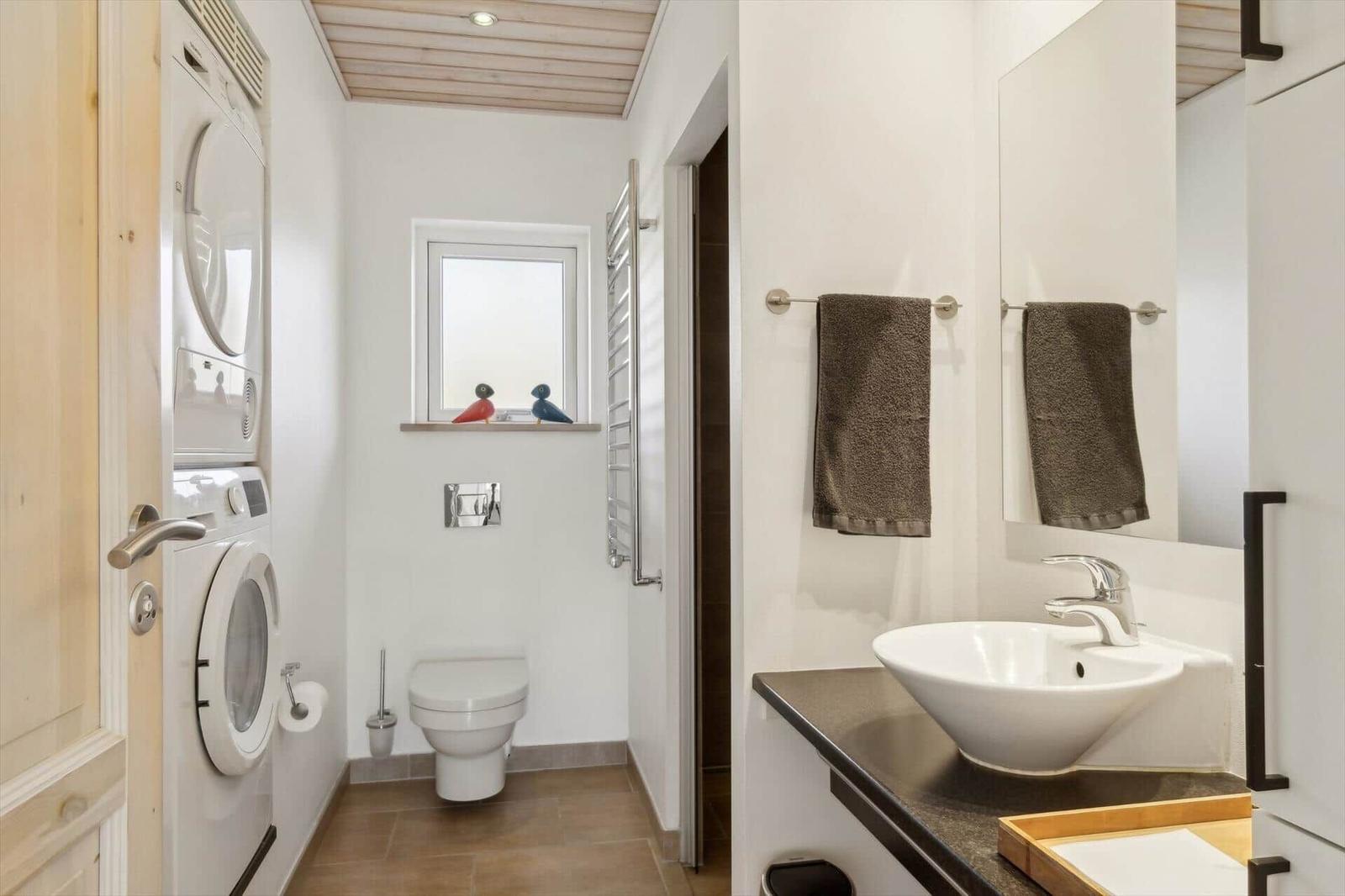 Badezimmer mit Waschmaschine, Toilette und Waschtisch