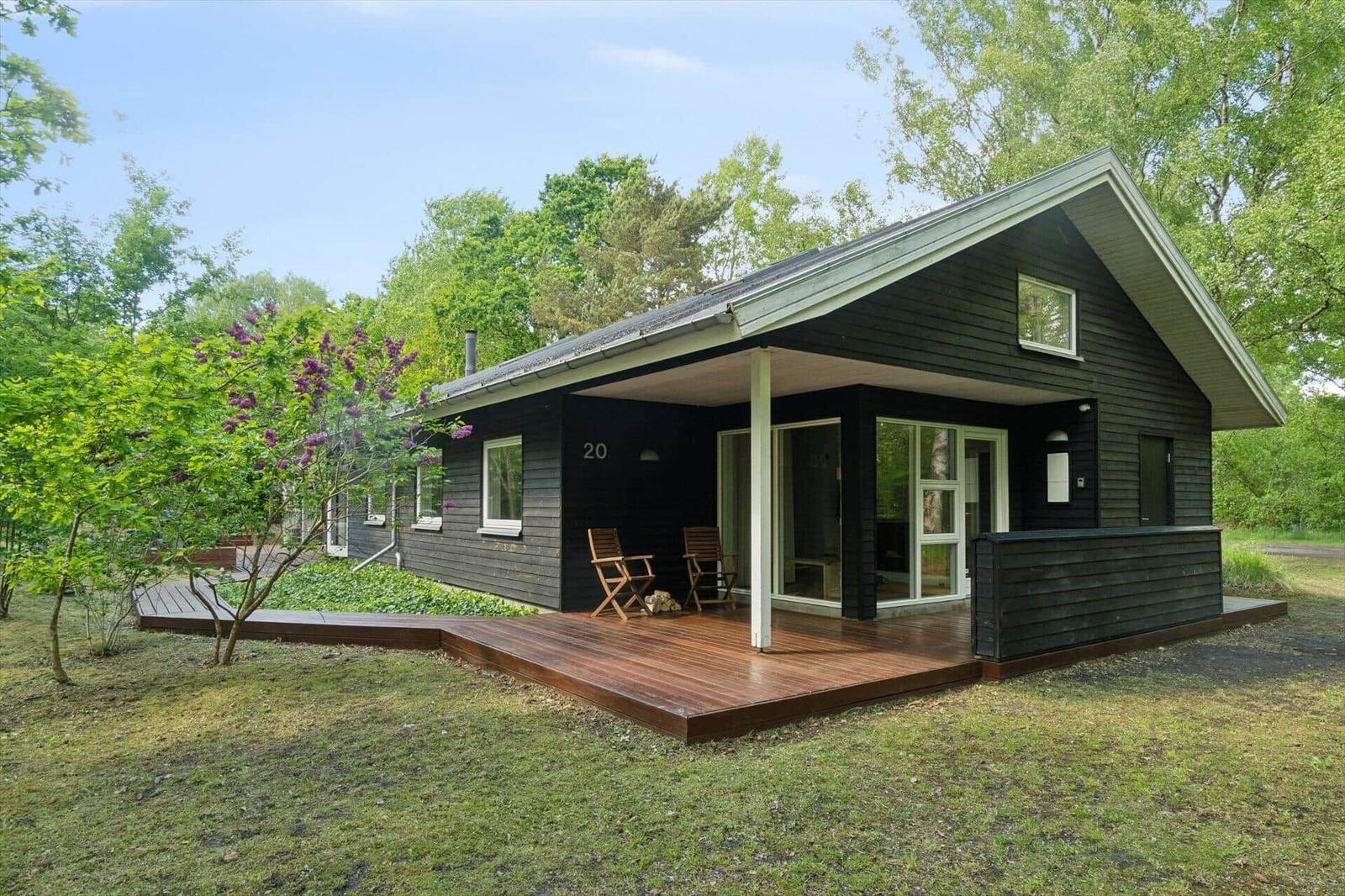 Moderne Holzhütte mit Terrasse und Garten. Holzveranda mit zwei Stühlen.