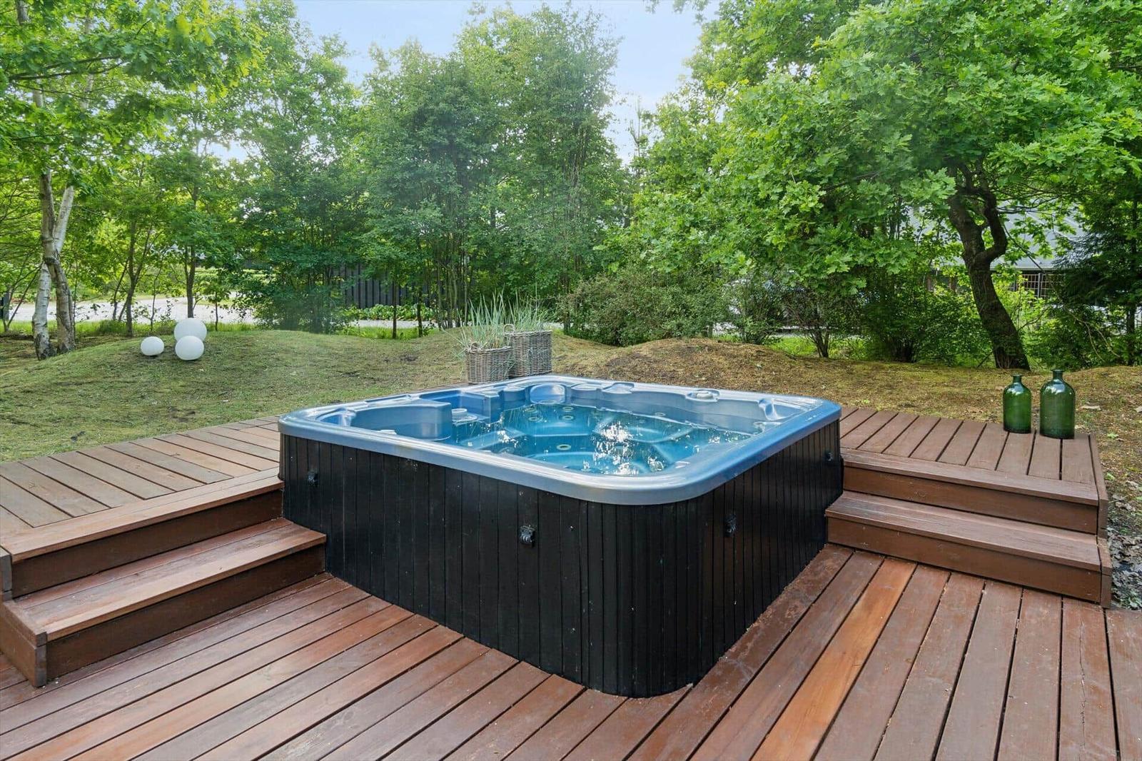 Hochwertige Whirlpool-Terrasse mit Holzdeck und grüner Umgebung.