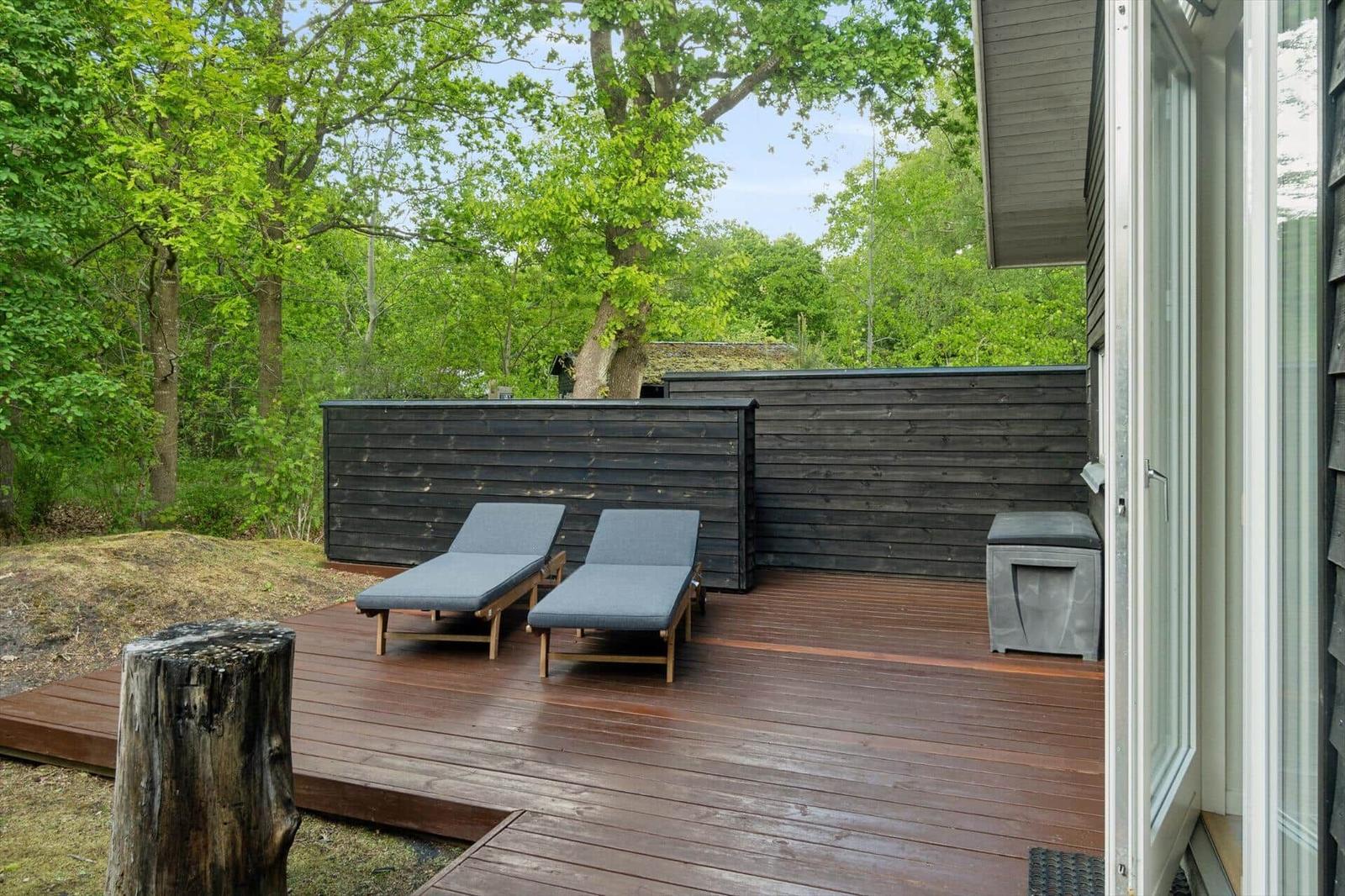 Terrasse mit zwei Liegen und Holzgeländer im Grünen.