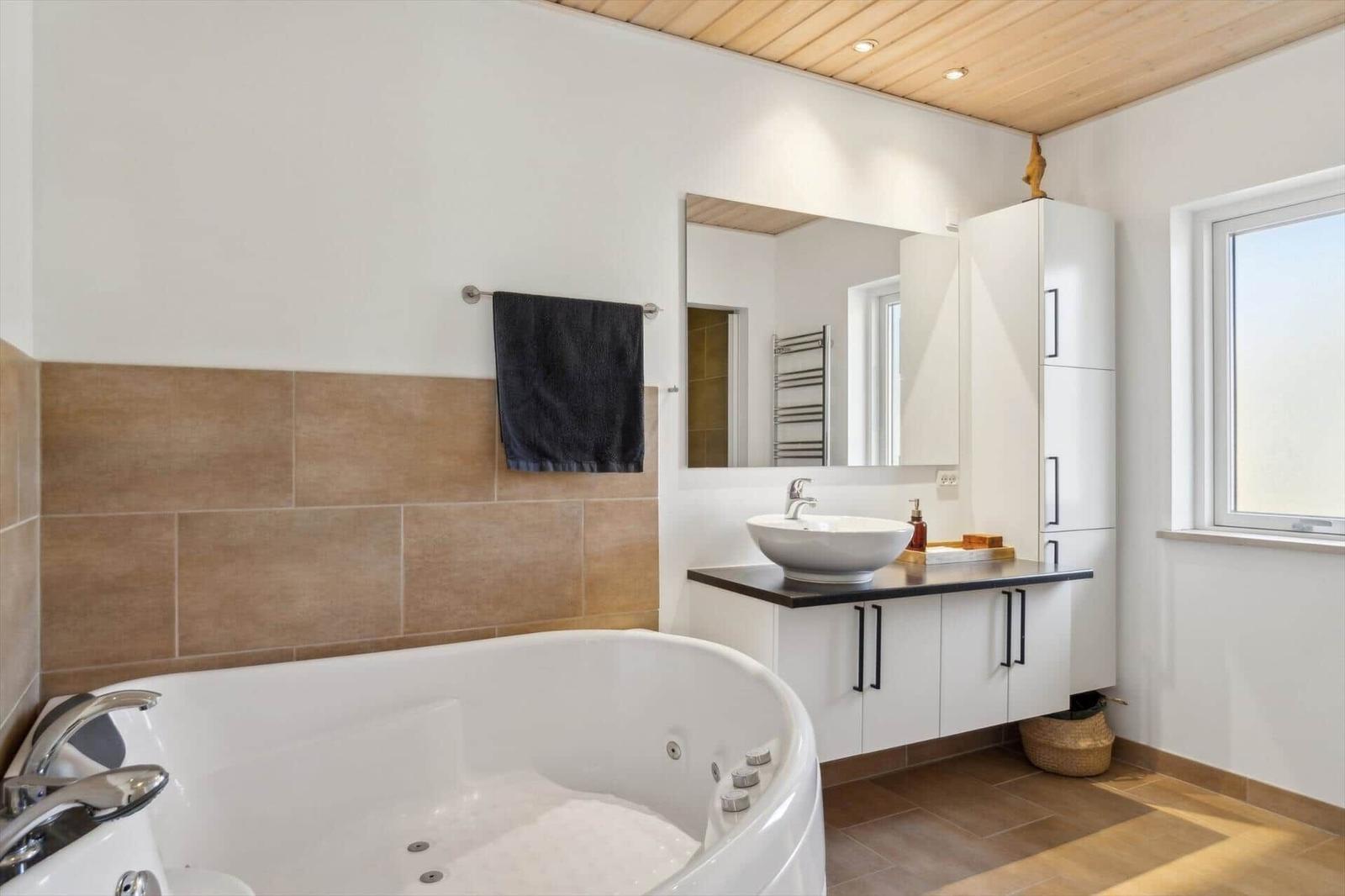 Bad mit Whirlpool, Waschbecken und Spiegelschrank.