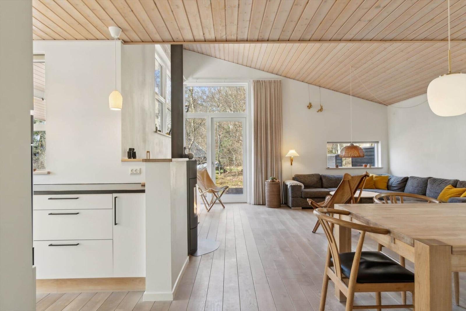 Offener Raum mit Küchenbereich, Essbereich und Wohnbereich. Holzdecke und -boden.